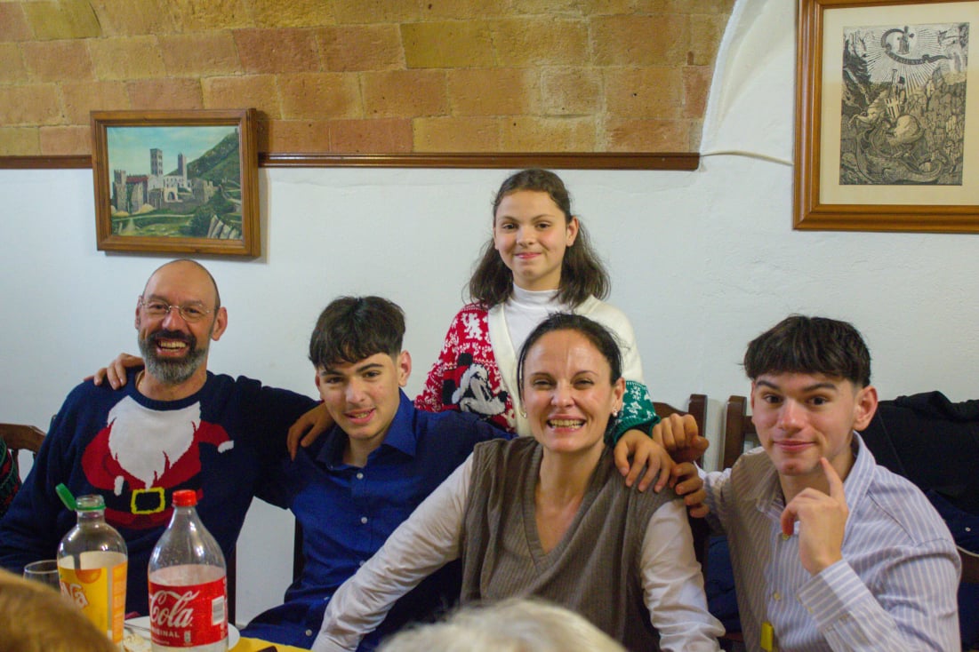 La familia reunida alrededor de una mesa, sonriendo en un ambiente cálido y familiar.